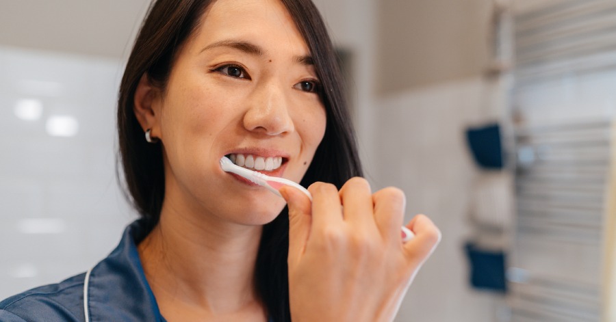 Woman brushing teeth, to avoid cavities and stains.
